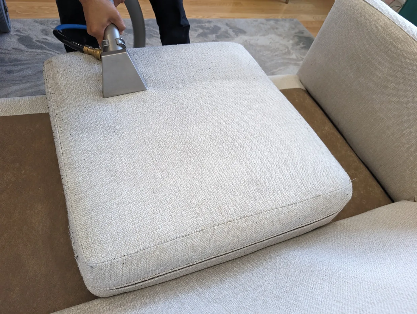 Close-up of an extraction tool cleaning a cream sofa cushion during one of our visits