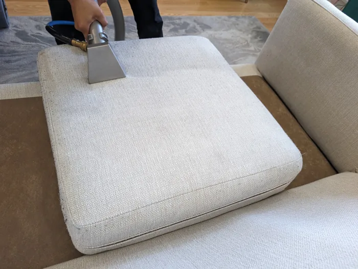 Handheld extraction tool on a cream sofa cushion