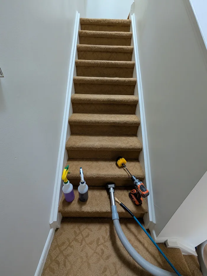 Carpeted staircase with cleaning tools on the lower steps