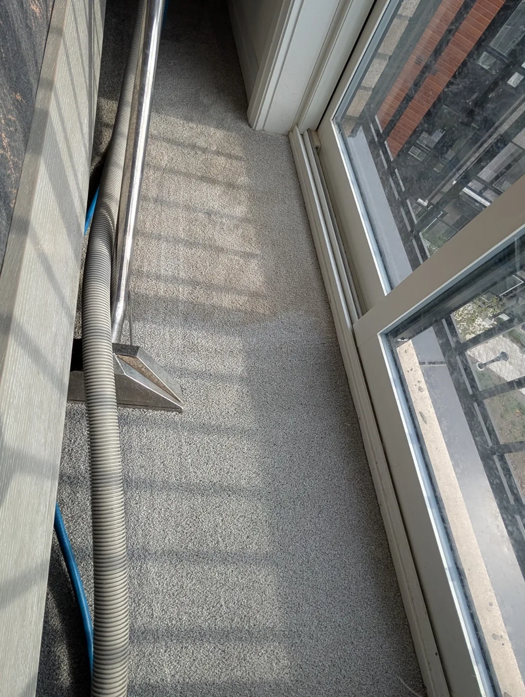 Carpet extraction wand beside a glass balcony door